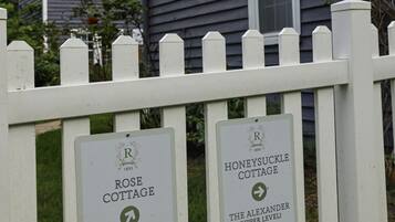 A white picket fence with signs indicating directions to various cottages.