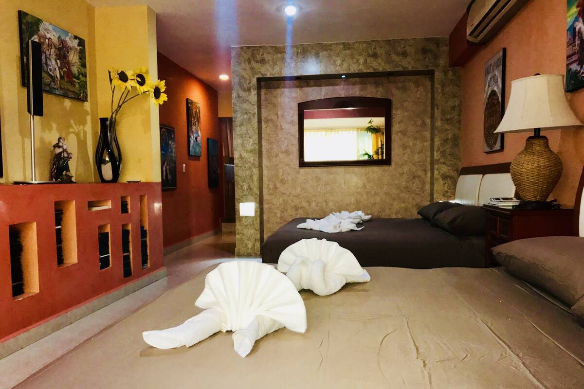 A hotel room with a bed, a nightstand, a lamp, and a wall-mounted TV.