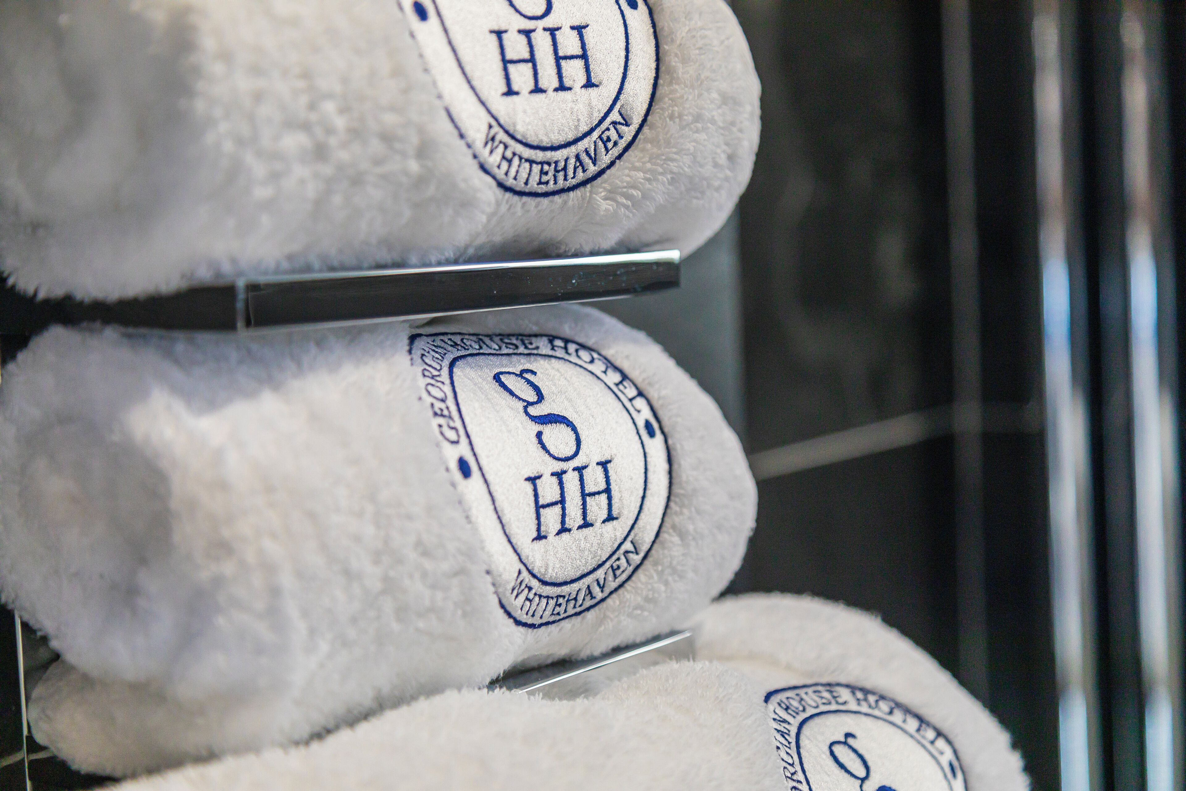 A stack of white towels with embroidered logos and text indicating they are from the Whitehaven hotel.