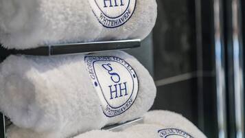 A stack of white towels with embroidered logos and text indicating they are from the Whitehaven hotel.