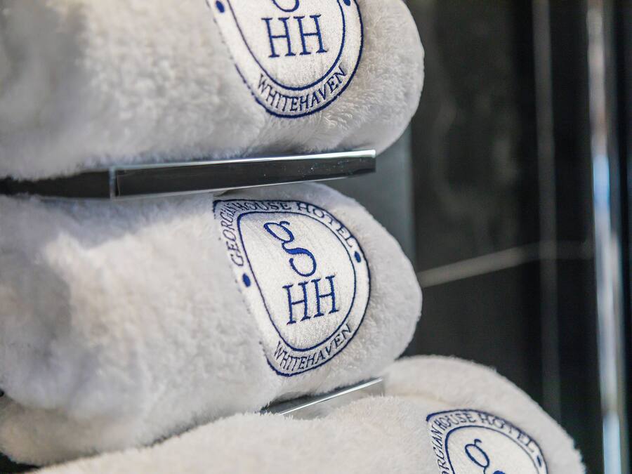 Una pila de toallas blancas con logotipos bordados e indicación de que son del hotel Whitehaven.