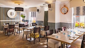 A dining area with a long table, chairs, and a clock on the wall. - Georgian House Hotel (Whitehaven)
