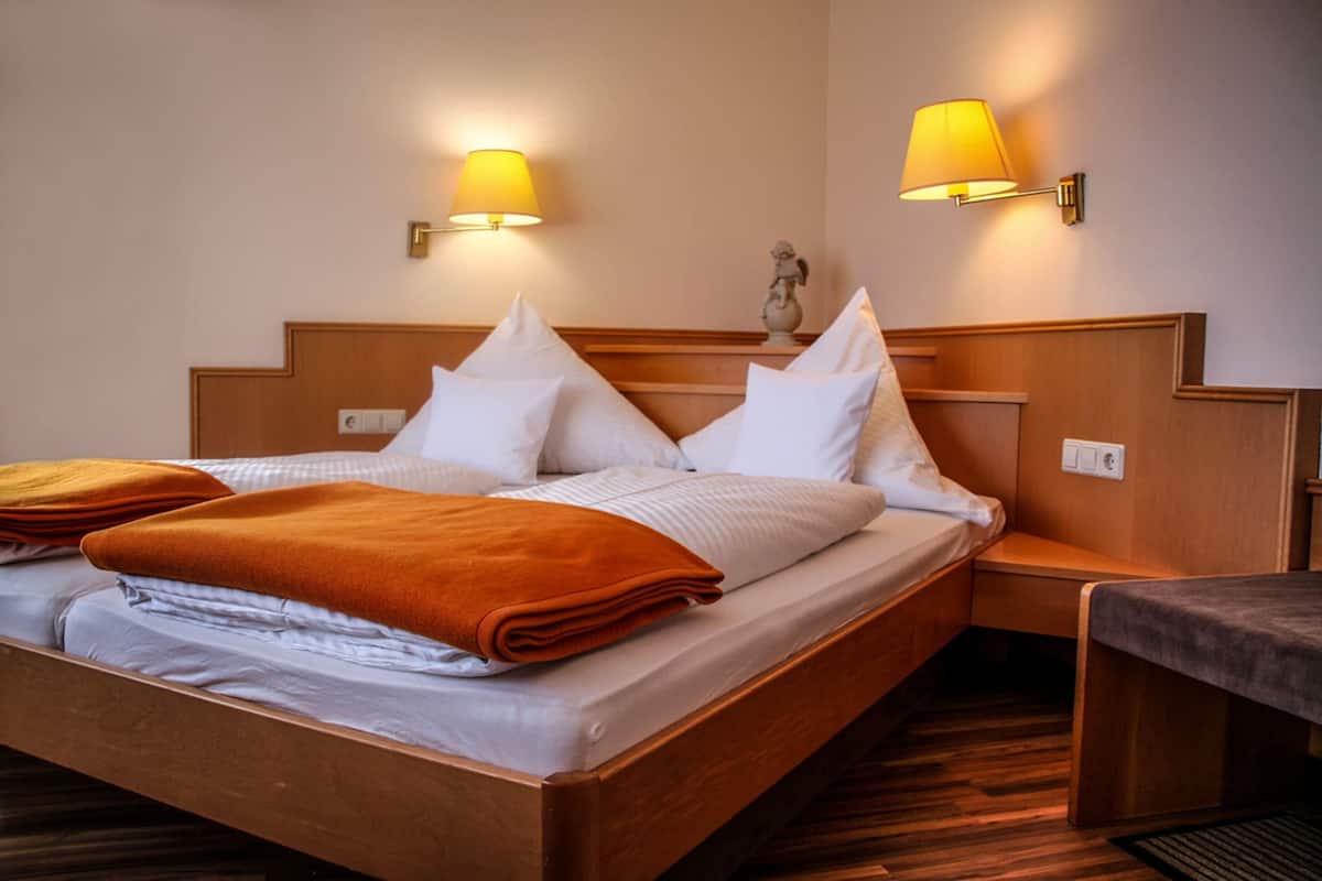 Een hotelkamer met een houten bed, twee bedlampen, een nachtkastje en een klein tafeltje.