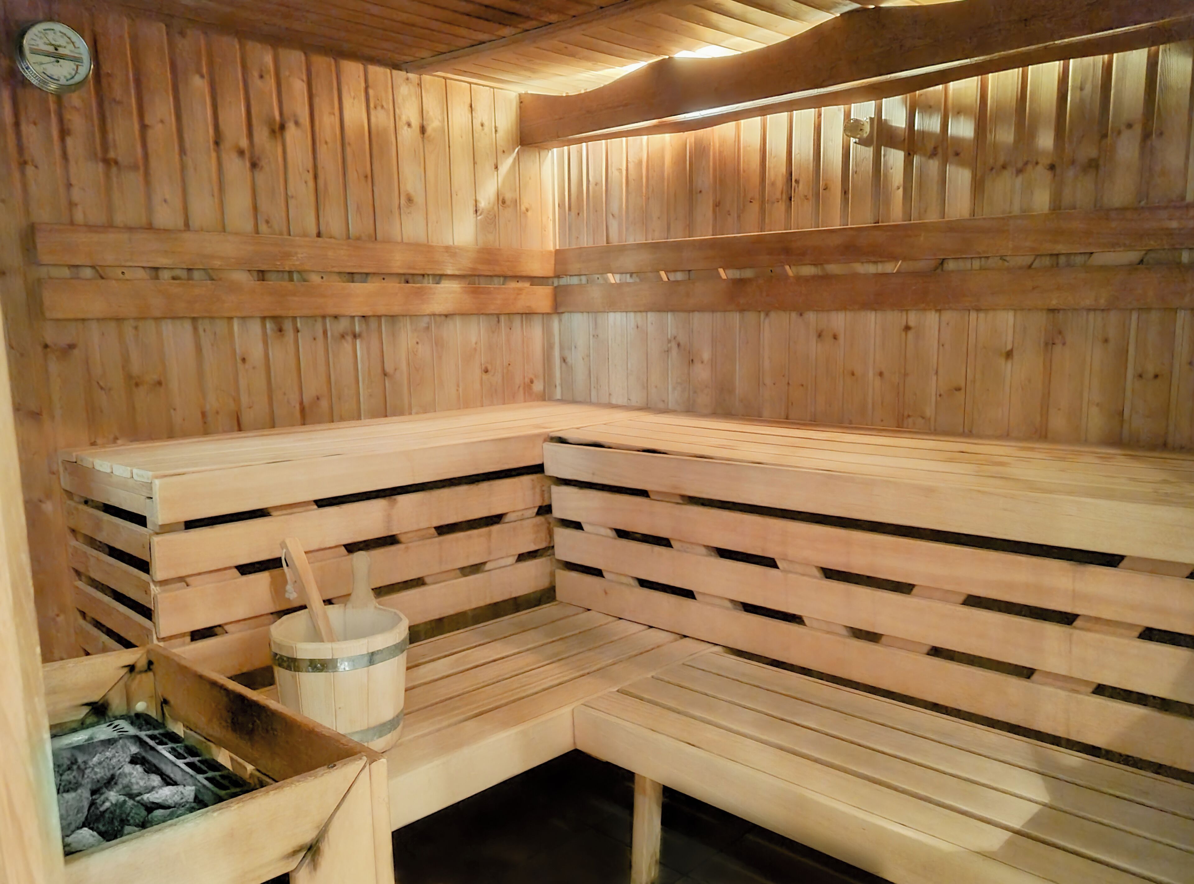 A wooden sauna with benches and a bucket.