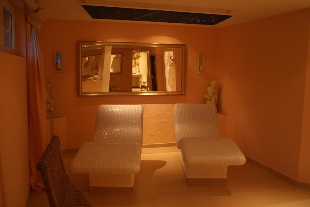 Ein Zimmer mit zwei gepolsterten Sitzbereichen, einem großen Spiegel und einer Statue an der Wand.