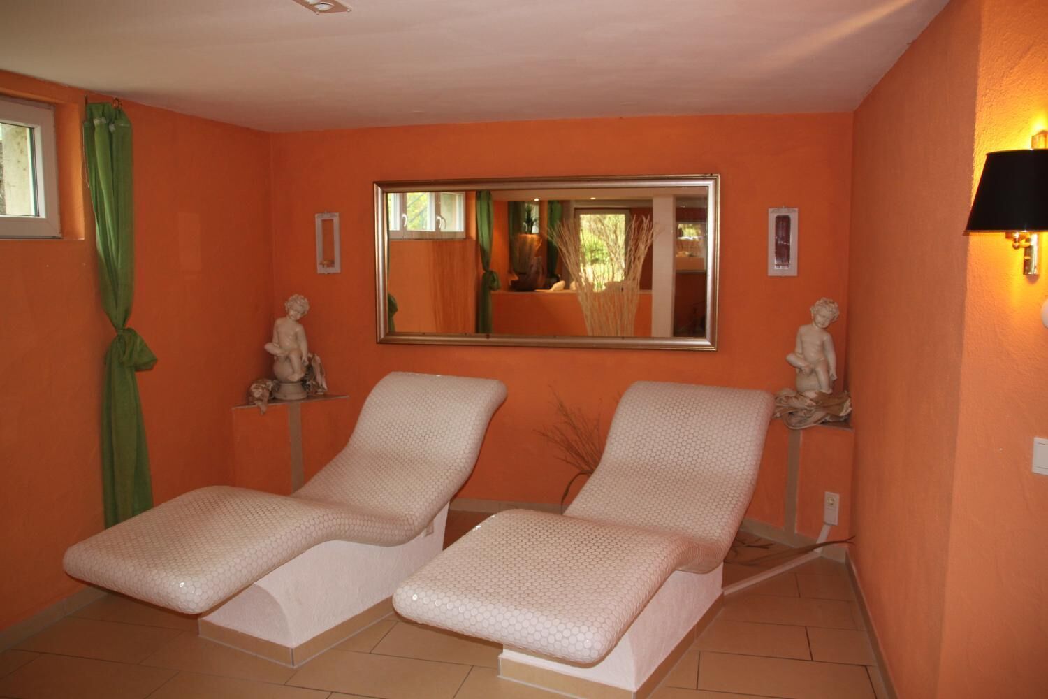 A room with two reclining chairs, a large mirror, and two small statues on shelves.
