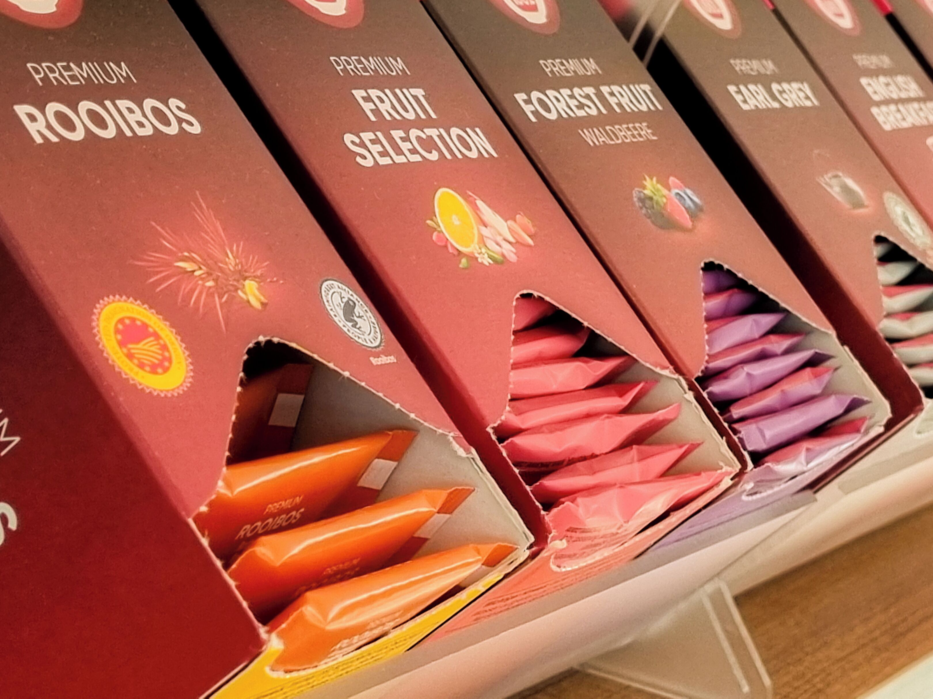 Eine Präsentation hochwertiger Obstschachteln mit Aufschriften wie 'Premium Rooibos' und 'Premium Obstauswahl'.