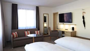 Una habitación de hotel con un sofá, un escritorio, un televisor y dos camas.