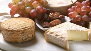 Una variedad de quesos y uvas en un plato.