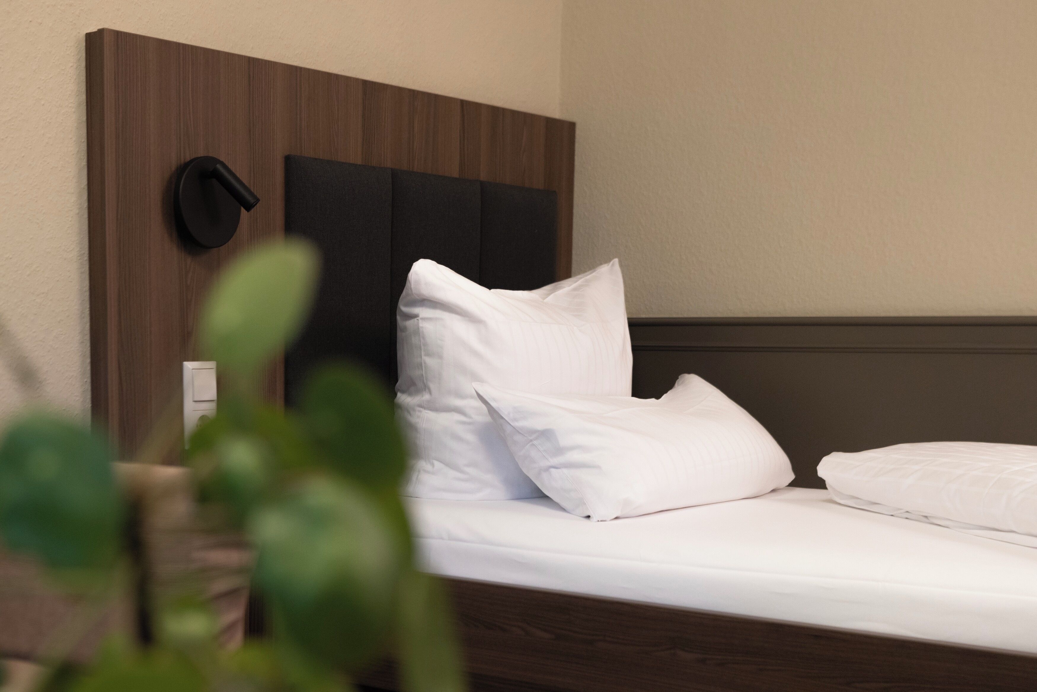 A neatly made bed with white linens and a wooden headboard.