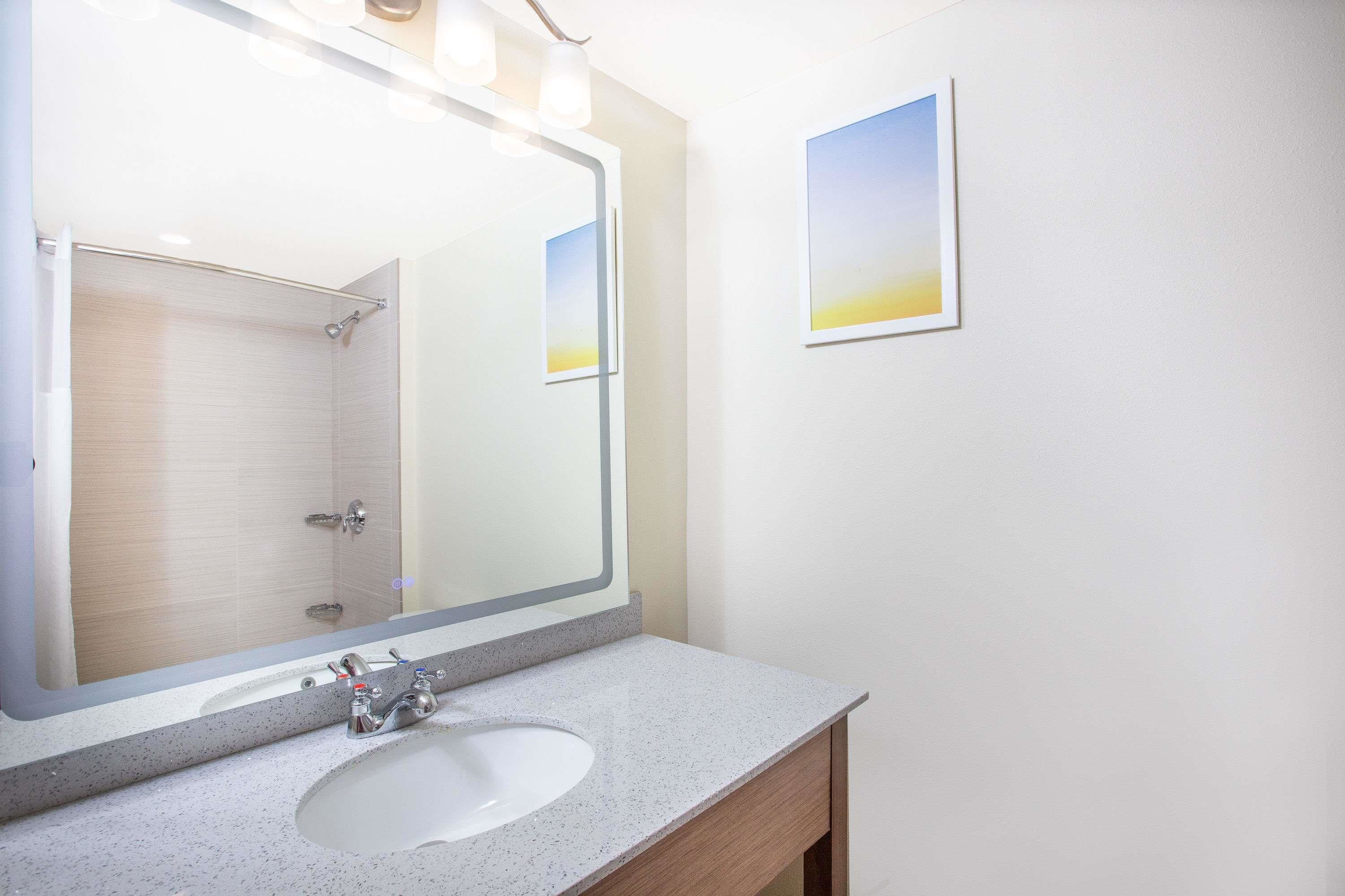 A bathroom with a large mirror, a sink, and a shower.