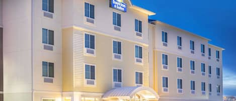 A Days Inn & Suites hotel with a modern facade, multiple windows, and a well-lit entrance.