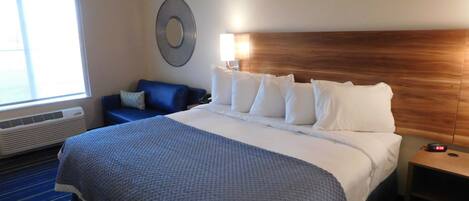 Ett hotellrum med en stor säng, en blå soffa, en rund väggdekoration och ett nattduksbord med en lampa.