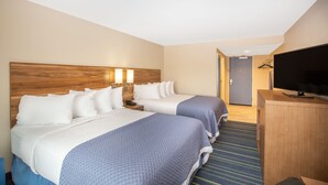 Habitación de hotel con dos camas, televisión y escritorio.