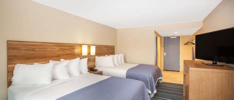 A hotel room with two beds, a TV, and a desk.