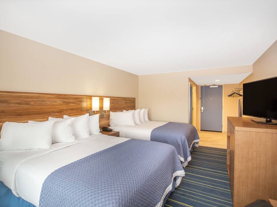 A hotel room with two beds, a TV, and a desk.
