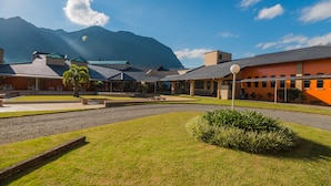 A hotel courtyard with a central seating area, a small palm tree, and a mountain backdrop. - Estância Ribeirão Grande (Jaragua do Sul)