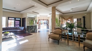 A spacious lobby with a curved sofa, a glass coffee table, and a seating area with chairs and a glass table. - Estância Ribeirão Grande (Jaragua do Sul)