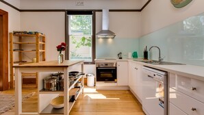 Une cuisine moderne avec des armoires blanches, un plan de travail en bois et un four encastré.