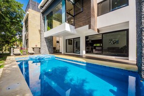 Een modern huis met een zwembad, grote ramen en een patio.