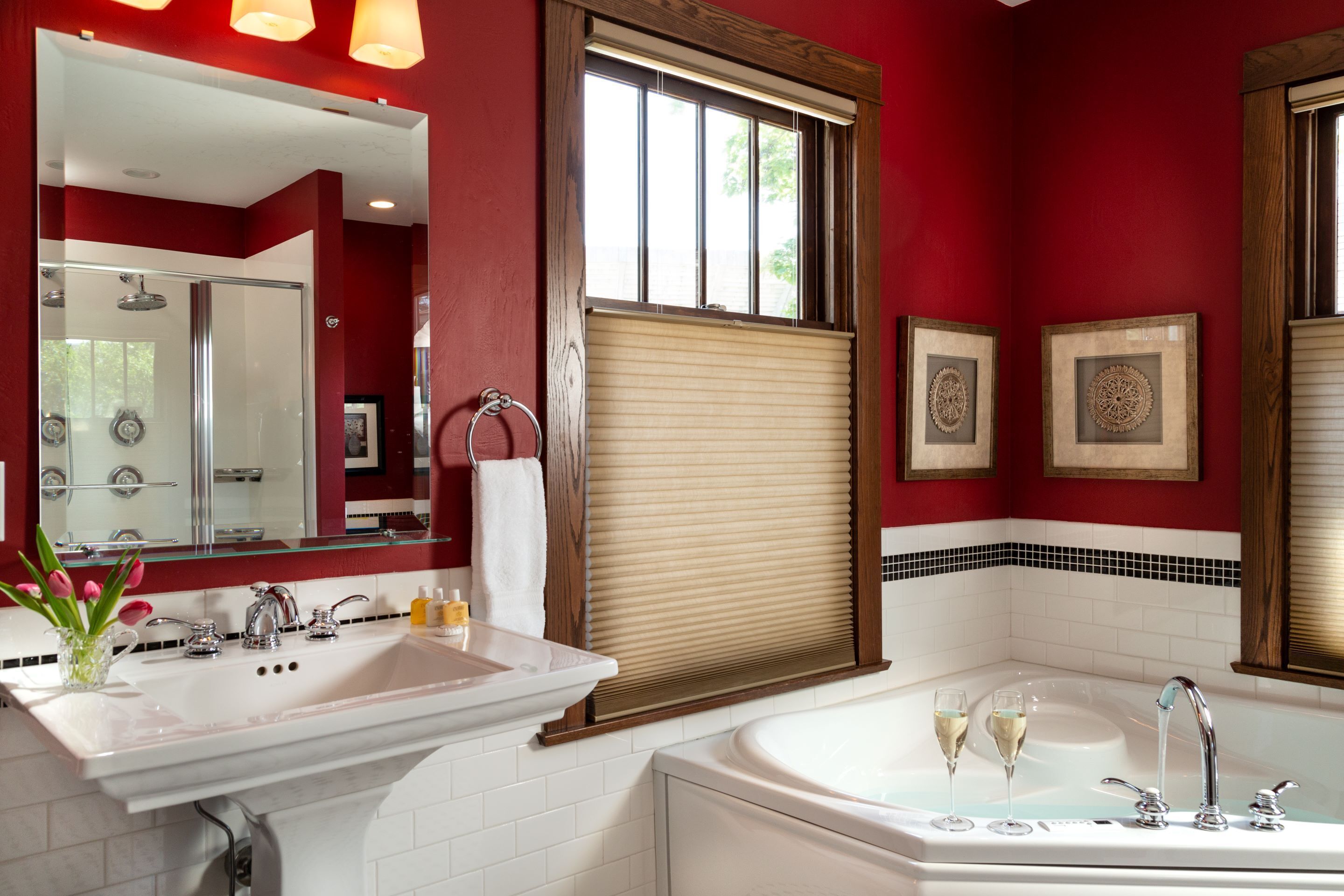 A modern bathroom with a large mirror, a sink, a bathtub, and a window with blinds.