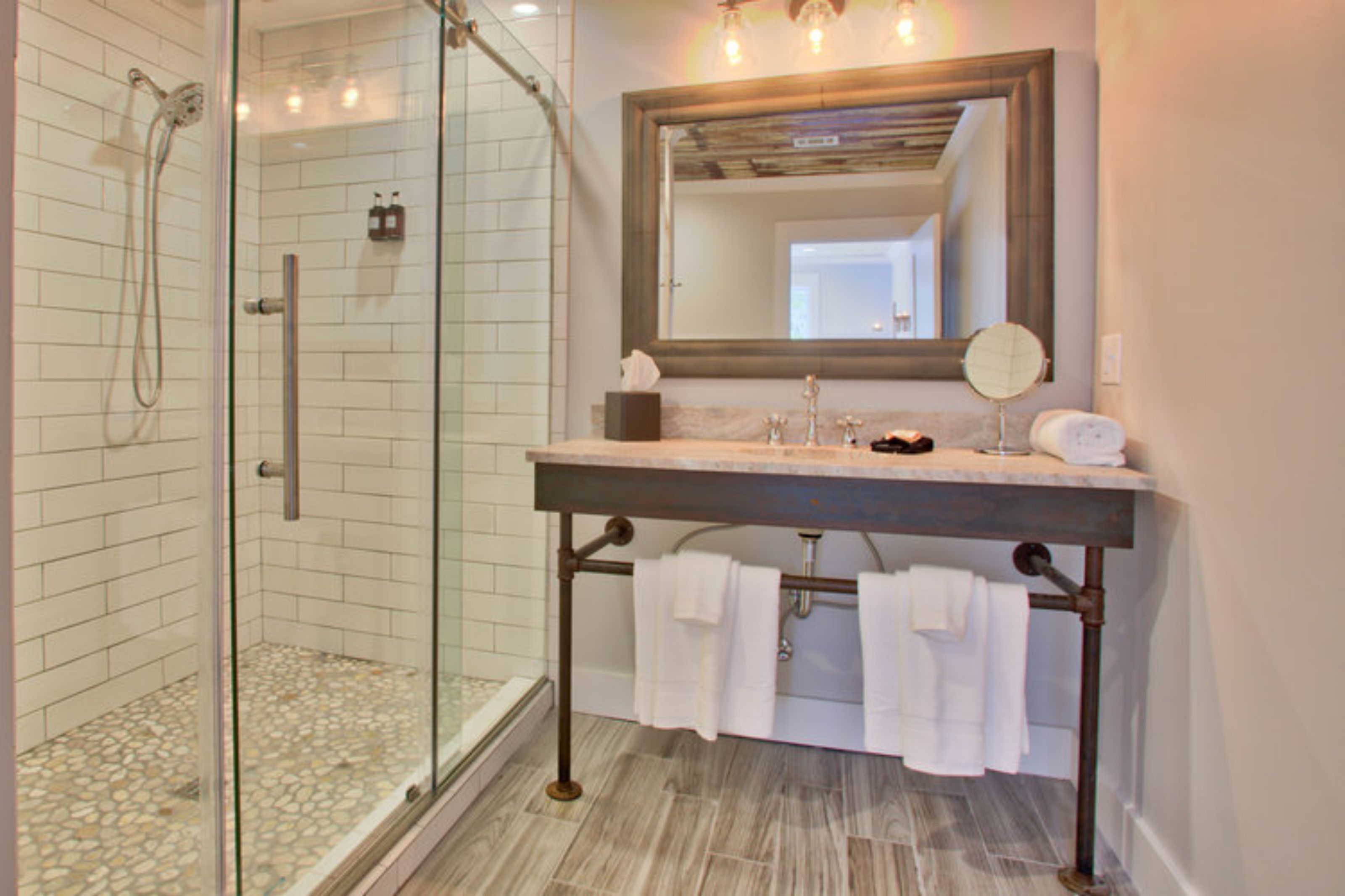 A bathroom with a glass-enclosed shower, a vanity with a mirror, and a towel rack.