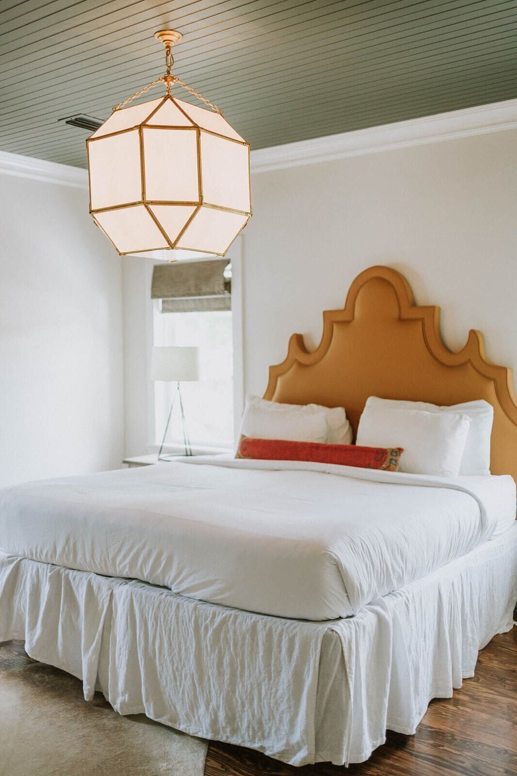 A bedroom with a large bed, a wooden headboard, and a hanging light fixture.