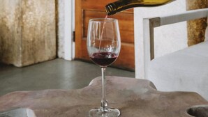 A hand pouring wine into a glass in front of a door labeled "The Wilbur".
