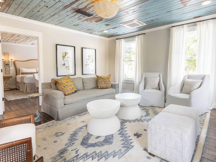 A living room with a sofa, two armchairs, a coffee table, and a patterned rug.