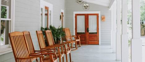 A covered porch with wooden rocking chairs and a ceiling fan.