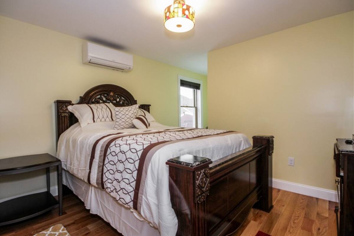 Une chambre à coucher avec un lit en bois, une table de chevet et une commode.