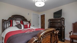 Une chambre à coucher avec un lit en bois, une commode et un téléviseur posé sur un meuble.