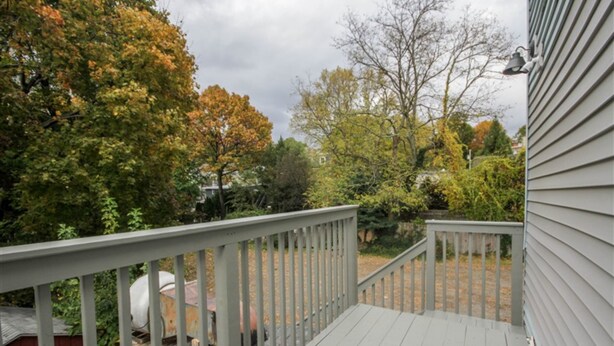 Une terrasse en bois dotée d’une rambarde, entourée d’arbres aux feuilles d’automne.