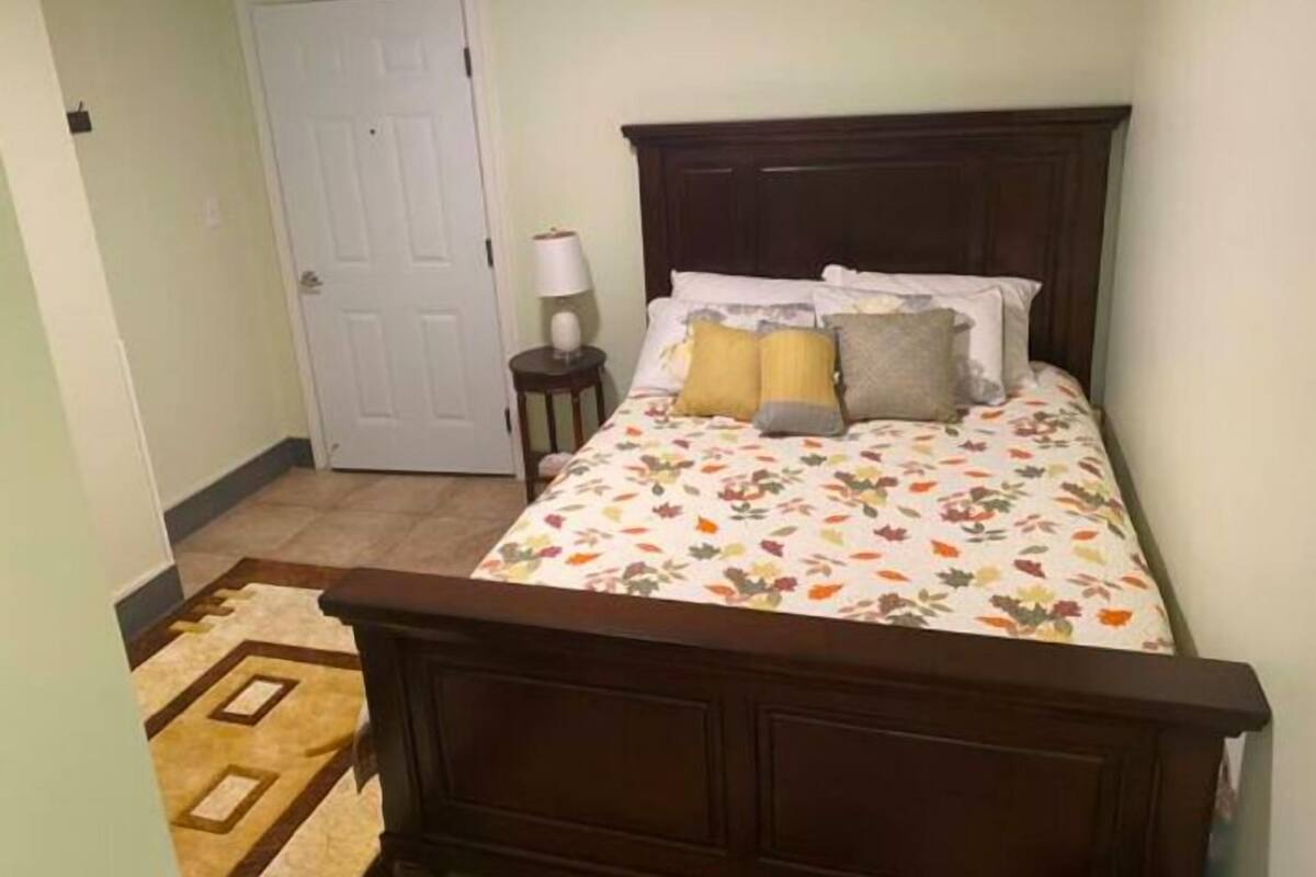 Une chambre à coucher avec un lit en bois, une literie à motifs floraux, une lampe de chevet et un tapis à motifs.
