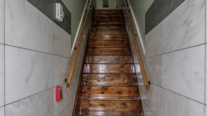 Un escalier en bois, avec des murs en marbre et un détecteur d’incendie sur le côté gauche.