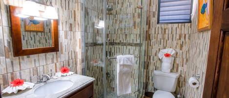 Ein Badezimmer mit einer Duschkabine, einem Waschbecken mit Spiegel und einer Toilette.