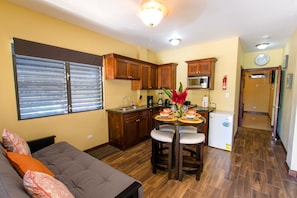 Cozy living area with sofa, dining table, and kitchenette, perfect for a small family or couple.