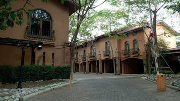 A courtyard with a building featuring a balcony and a gated entrance.