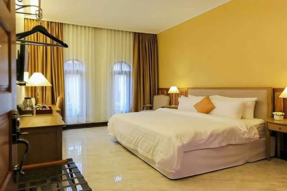 A hotel room with a bed, bedside tables, a desk, and a chair.