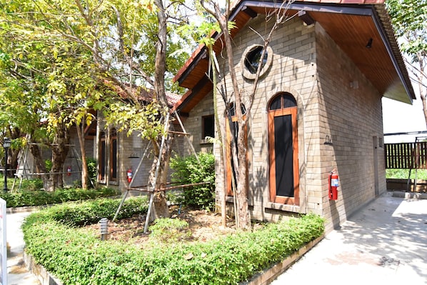A brick building with a wooden roof, a circular window, and a fire extinguisher mounted on the wall.