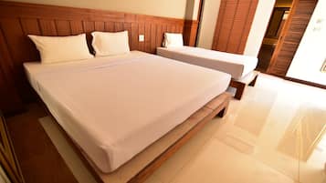 Habitación de hotel con una cama grande, una cama más pequeña, cabecera de madera y un armario de madera.