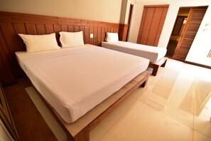 A hotel room with a large bed, a smaller bed, wooden headboard, and a wooden wardrobe. - Fantasy Resort (Nakhon Sawan)