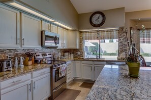 Enjoy cooking in this well-equipped kitchen with a granite countertop, stainless steel appliances, and ample storage.