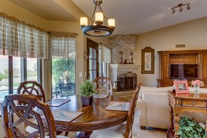 Relax in this inviting living room with a dining table, fireplace, and mounted TV.