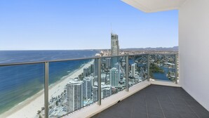 A balcony with a clear view of a beach, ocean, and cityscape including a tall building. - 5*****Star Luxury 51 floors High (Surfers Paradise)