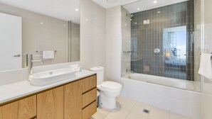 A modern bathroom with a large mirror, a sink, a toilet, and a glass-enclosed shower area. - 5*****Star Luxury 51 floors High (Surfers Paradise)