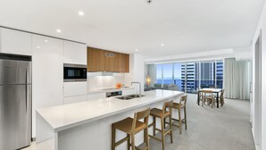 A modern kitchen with a central island, stainless steel appliances, and a dining area with a view of the city. - 5*****Star Luxury 51 floors High (Surfers Paradise)