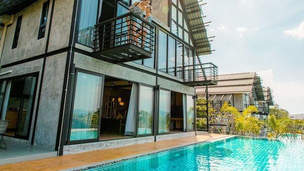 En moderne toetagers bygning med en glasbalkon med udsigt over en swimmingpool.