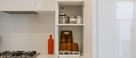 A kitchen with a gas stove, a coffee maker, and a wooden cutting board.
