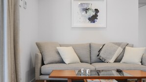 Ein Wohnzimmer mit einer Couch, einem Couchtisch und einem gerahmten abstrakten Gemälde an der Wand.